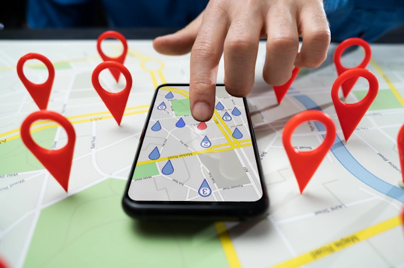 a hand touching a phone with a map and red pointers in search for local business
