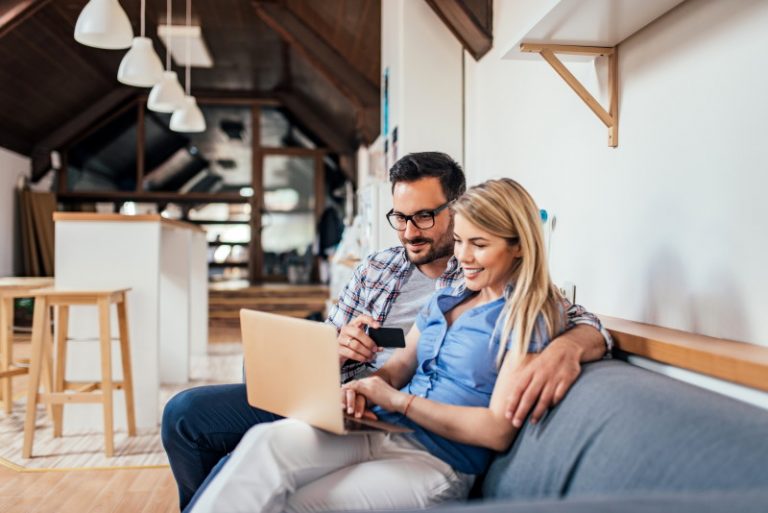 a lovely couple sitting in a couch with a happy face while looking on new seo book for everyone