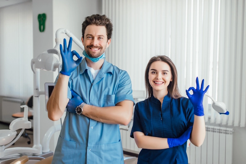 Two dentists in uniforms making "okay" gestures while boosting their practice with SEO for dentists.